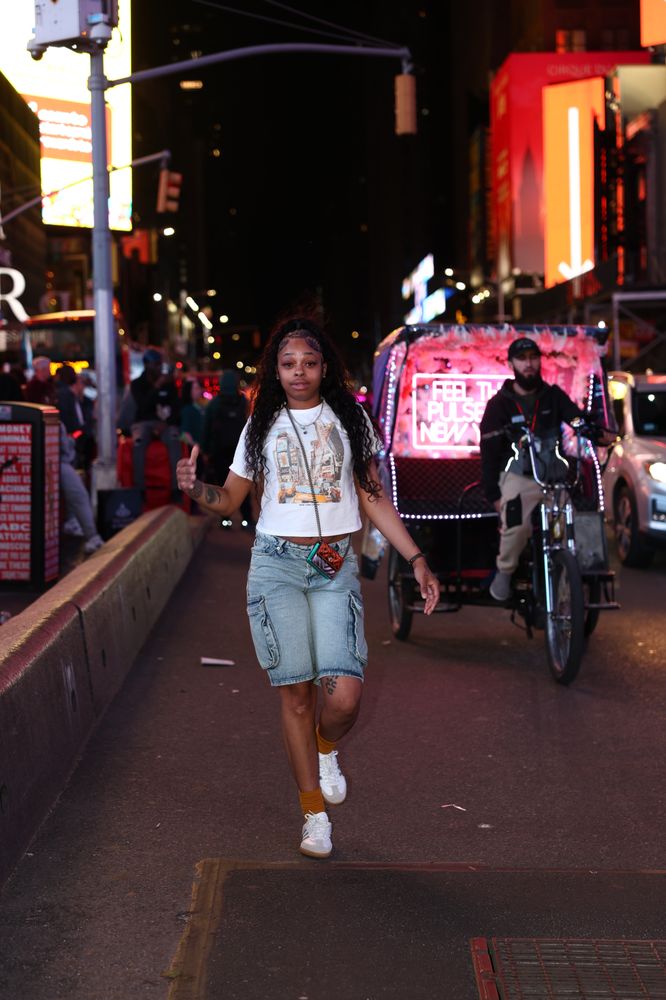 Woman walking through Times Square with neon lights behind her